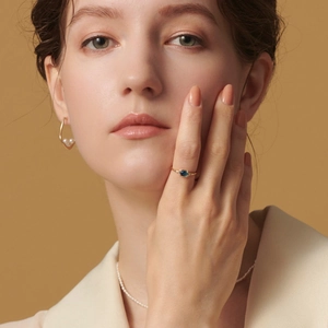 Close-up of gold ring with blue topaz and pearl earrings on female model