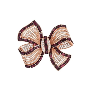 Macro shot of rose gold bow brooch featuring a red gemstone and crystal detailing