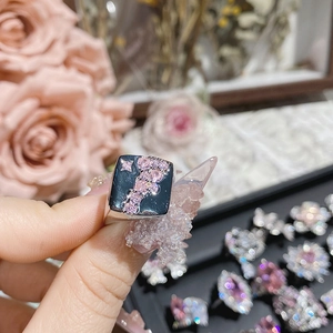 Detailed close-up of a luxury pink gemstone ring with star motifs and cascading stones