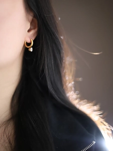 Close-up of a 18K gold plated hoop earring with a sparkling clear zircon pendant