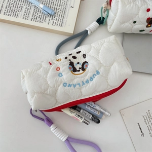Close-up detail of a white quilted pencil case featuring cute puppy embroidery.