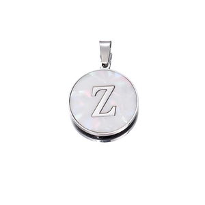 Detail shot of a round silver pendant featuring a white shell inlay and metal letter Z