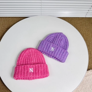 Detail of knit hats with embroidered N letter in magenta and purple winter yarn