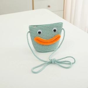 Détail du sac en paille tressée menthe avec yeux de dessin animé et bouche en peluche