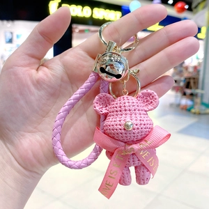 Macro detail of pink resin bear keychain with woven texture and a decorative bow