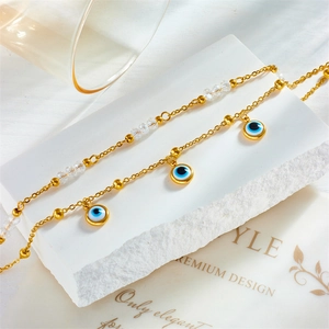 Multi-layered gold titanium steel anklet with blue evil eye pendant and clear beads