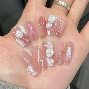 Detailed macro shot of 3D rose and pearl accents on pink gradient press-on nails