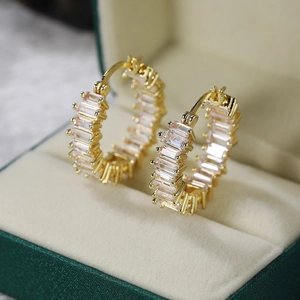 Detail of gold hoop earrings with claw-set rectangular AAA cubic zirconia in a jewelry box