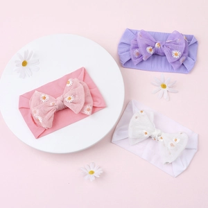 Three baby headbands with daisy embroidery on mesh bows in pink, purple, and white colors