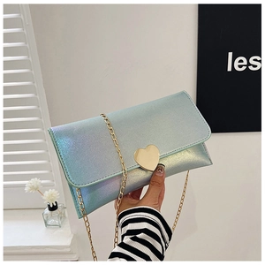 Detail of gradient heart handbag with gold chain strap and heart metal clasp held by hand