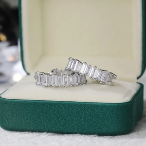 Macro detail of silver tone earrings with emerald cut cubic zirconia in a luxury green box