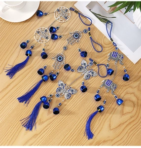 Macro detail of metal wind chimes featuring Tree of Life and Evil Eye charms on wood