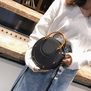 Modern black circular shoulder bag with gold hardware and metal ring handles
