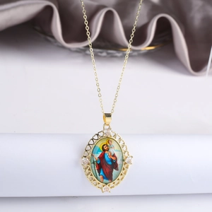 Dettaglio del ciondolo religioso dorato con zirconi e bordo traforato a cuore