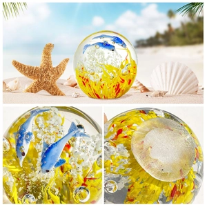 Macro detail of a glass paperweight with blue dolphins and coral inside a crystal wave ball