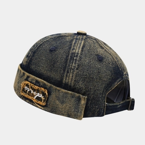 Detail of distressed denim docker hat with vintage wash finish and embroidered patch
