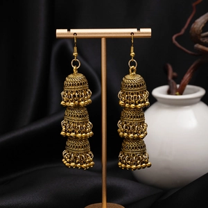 Detail of vintage gold-tone triple-layer Jhumka earrings with bells on a stand