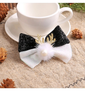 Close-up of Christmas antler hair clip with black bow, white pompom and gold sequins