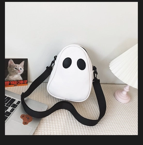 Detail of cute white ghost-shaped PU crossbody bag with large black eyes and fabric strap
