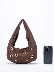 Detailed view of burgundy suede shoulder bag with gold metal eyelets and studs