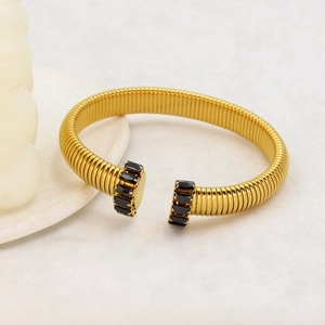 Dettaglio macro del bracciale rigido a C placcato oro 18K con zirconi neri taglio baguette