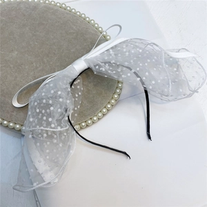 Detail of white lace polka dot bow headband with long ribbons on a decorative tray