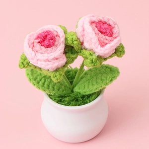 Handmade crochet pink roses in a white ceramic-style pot on a soft pink background