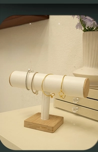 Detail of single-bar T-stand for jewelry with white cylinder and solid wood base