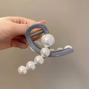 Detailed shot of large white pearls on a grey hair claw clip with spring mechanism