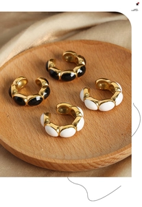 Macro shot of gold-plated U-shaped ear cuffs with black and white enamel inlays