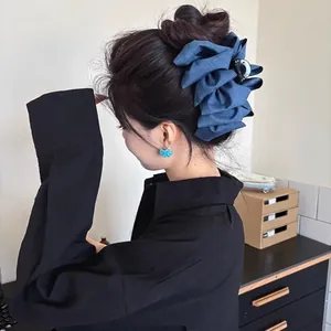 Detail of dark blue denim bow hair claw clip styled on a messy bun hair style