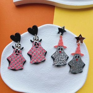 Detail of Halloween acrylic glitter earrings with ghost designs on a white tray