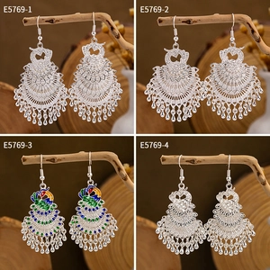 Macro shot of silver peacock drop earrings with colorful enamel and fringe beads