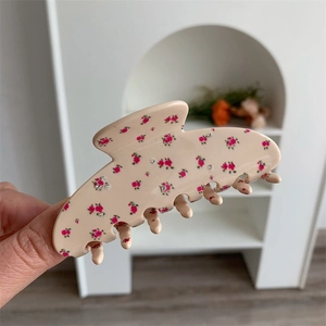 Close-up of beige acetate hair claw with pink floral patterns and silver rhinestones