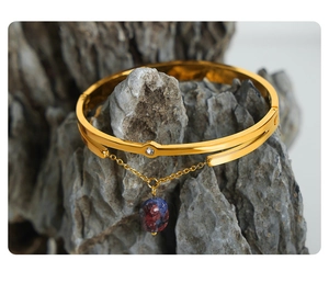 Detailed macro of gold-plated titanium steel bangle with marbled gemstone pendant