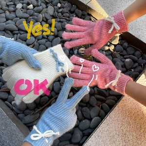 Detailed texture of knit gloves with bow accents in pink, blue, and white colors