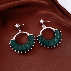 Detailed view of silver stud earrings with dark green fan-shaped leather and bead accents