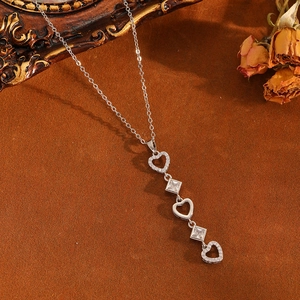 Détail du pendentif cœur en argent avec zircons sur un fond de tissu chaud