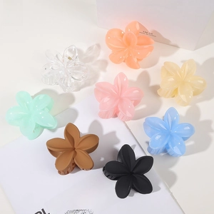 Top view of eight colorful gradient flower hair claws on a magazine and white box