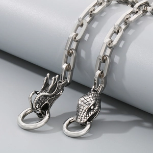 Detailed view of silver stainless steel chain bracelet with dragon and snake heads