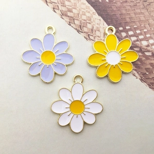 Detail of colorful enamel sunflower charms in purple yellow and white with gold metal frames
