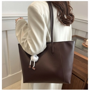 Vue détaillée d'un sac cabas marron minimaliste avec des bretelles et un pendentif peluche.