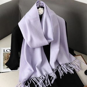 Dettaglio di morbida sciarpa lilla in finta cashmere con frange su abbigliamento nero