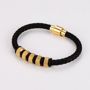 Detail of black braided leather men's bracelet with five gold knurled beads and magnetic clasp