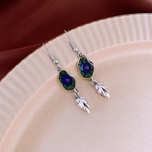 Macro shot of silver wheat spike fringe earrings with blue enamel and leaf pendants