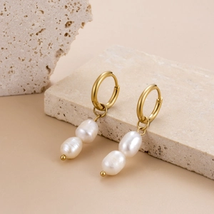 Elegant gold double ring earrings with hanging white pearls on a natural stone base
