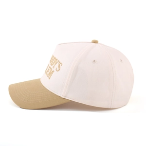 Detailed side view of two-tone baseball cap with cream crown and gold letter embroidery