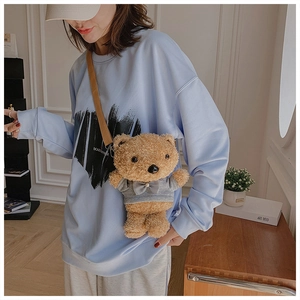 Detail of cute brown plush teddy bear crossbody bag featuring a grey sweater with a bow