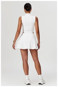 Detail eines weißen Yoga-Sets mit sportlichem Tanktop und plissiertem Tennisrock
