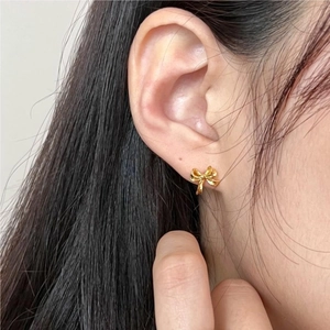 Close-up of elegant gold bow stud earrings worn on model for a minimalist jewelry look